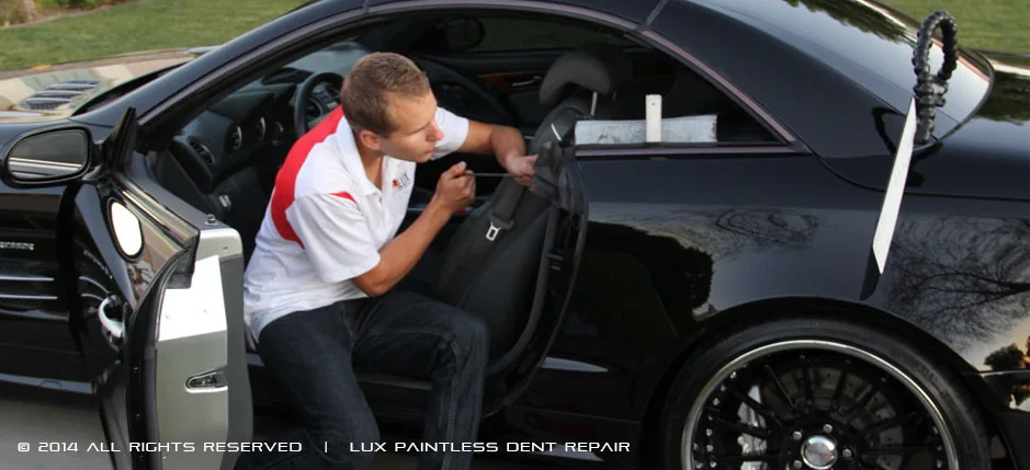 LUX PDR technician carefully repairing a black sports car